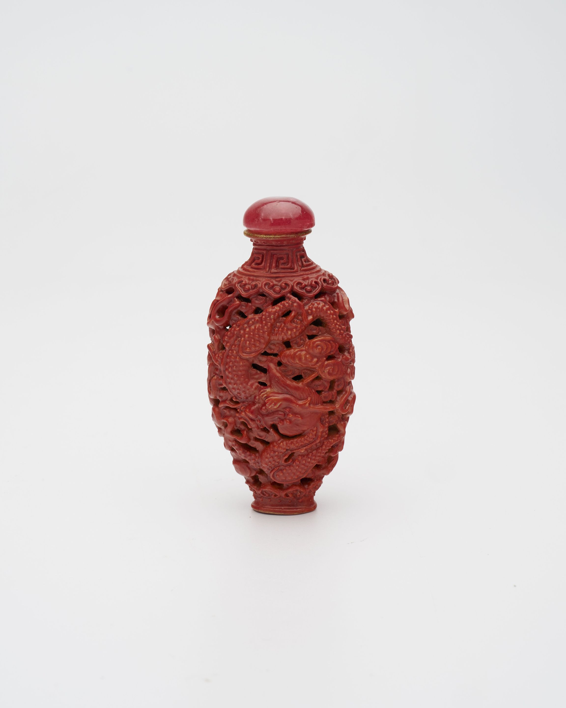 A CORAL-GLAZED AND MOULDED 'DRAGON AND PHOENIX' SNUFF BOTTLE Two-character 'Longevity' gilt mark, 19th century