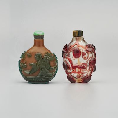 A GREEN OVERLAY BROWN GLASS 'MONK HOLDING A LOTUS' AND A RED OVERLAY GLASS 'SQUIRREL' SNUFF BOTTLE 19th century (2)